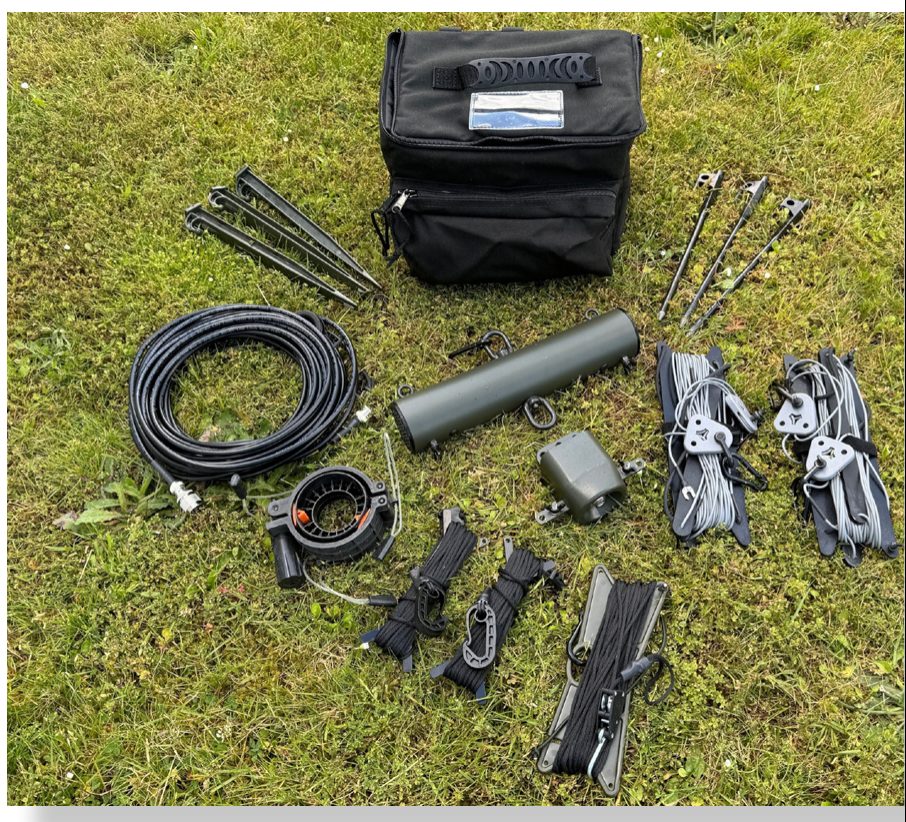 Complete HF Antenna Kit laid out on grass with bag, pegs, coaxial cable, resistor tube, balun and dipoles